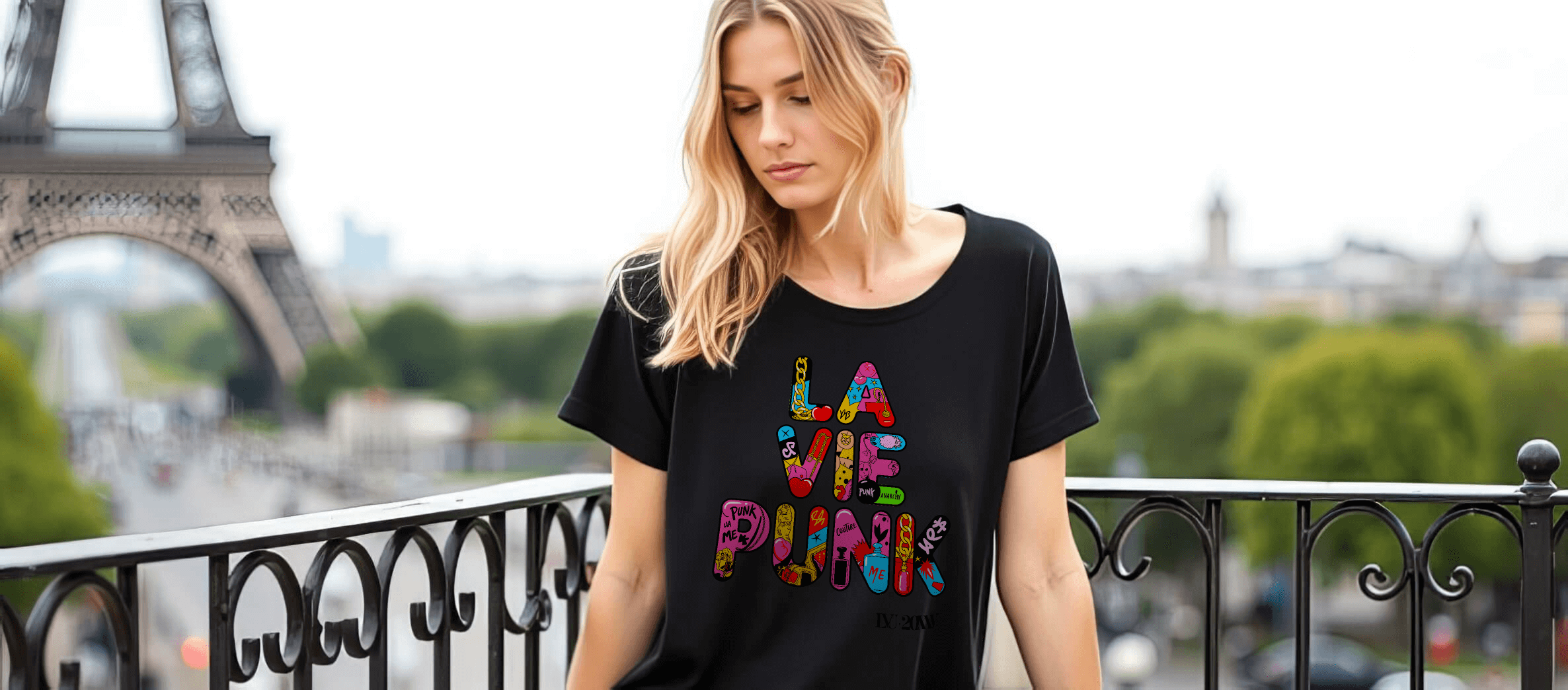 Model on a Paris balcony near the Eiffel Tower wearing a black La Vie Punk top with colorful multicolor graphic lettering.