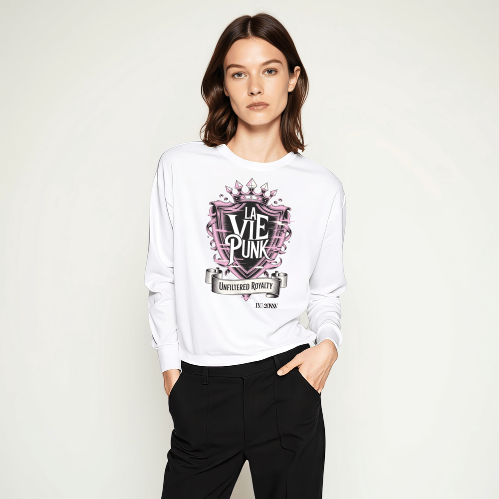 Model wearing white long-sleeve t-shirt with pink and black crown-inspired ‘LA VIE PUNK’ graphic and ‘Unfiltered Royalty’ banner, styled with black trousers in a studio setting.