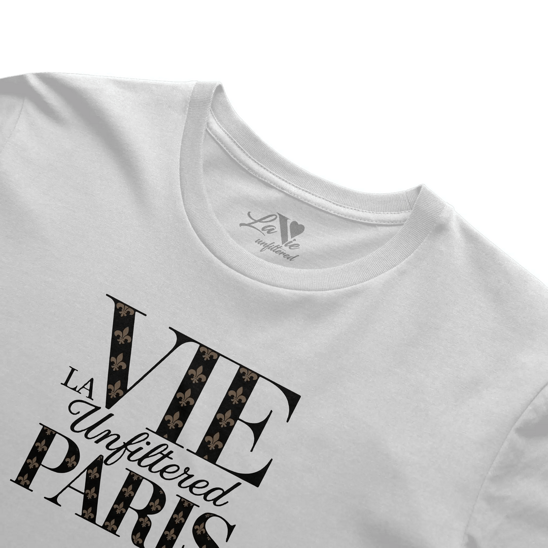 Close-up angled view of neckline and chest design of the white boxy fit tee, featuring 'La Vie Unfiltered Paris' with noir monogram details.