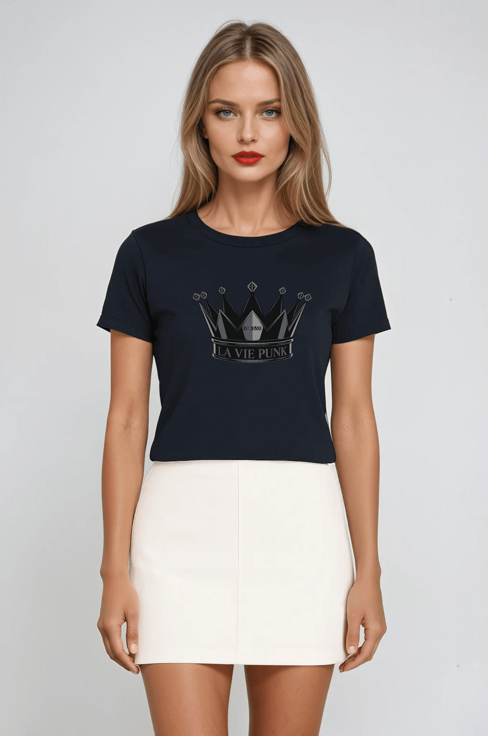 Model wearing the Throne Punk Allure jersey tee in black with bold crown graphic and 'La Vie Punk' lettering, paired with a white mini skirt, photographed against a minimalist gray background.